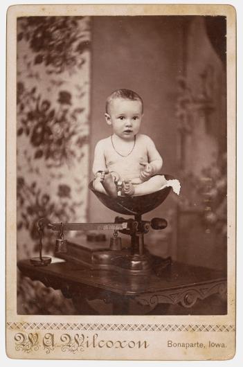 antique photograph of a baby sitting in a scale
